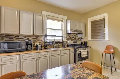 a kitchen with white cabinets and a table with chairs at Easy Commute to Newark and NYC! Extended Stay Unit in Irvington