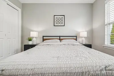 a white bedroom with a large bed with two lamps at Spacious 3BR Near Rutgers plus Princeton plus NYC Access in Franklin Park