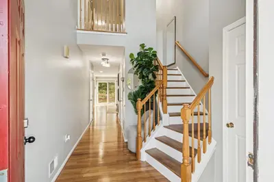 a hallway with white walls and a staircase with a plant at Spacious 3BR Near Rutgers plus Princeton plus NYC Access in Franklin Park