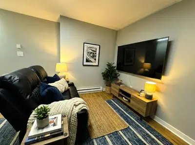 a living room with a black leather couch and a flat screen tv at Crossroads at Park Place in Wilmington