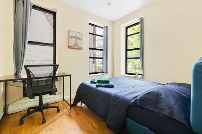 a bedroom with a bed and a desk and a chair at Spacious Central Park Apartments in New York