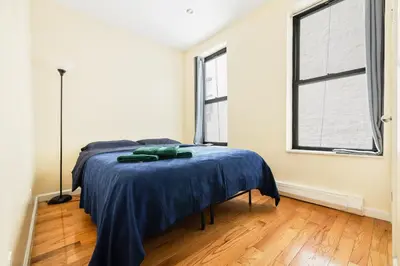 a bedroom with a bed with a blue blanket on it at Spacious Central Park Apartments in New York