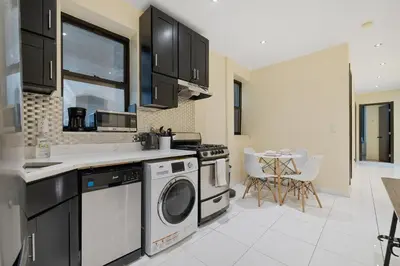 a kitchen with a washer and dryer and a table at Spacious Central Park Apartments in New York
