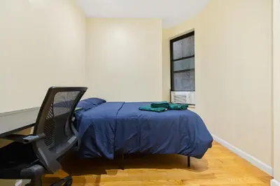 a bedroom with a bed and a desk and a chair at Spacious Central Park Apartments in New York