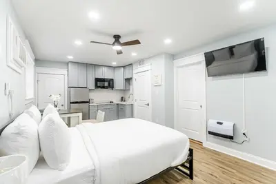 a white bedroom with a white bed and a kitchen at Studio Minutes from Center City South Philly Special in Philadelphia