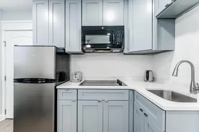a kitchen with white cabinets and a stainless steel refrigerator at Studio Minutes from Center City South Philly Special in Philadelphia