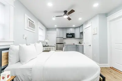 a white bedroom with a white bed and a kitchen at Studio Minutes from Center City South Philly Special in Philadelphia