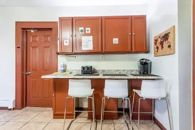 a kitchen with white bar stools and wooden cabinets at 1 Bus Stop To NYC Room-Free Parking in Hillside