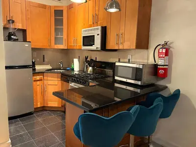 a kitchen with wooden cabinets and blue chairs in it at The Marlow Midtown in New York