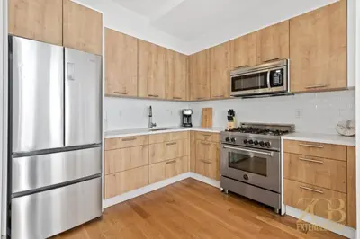 a kitchen with wooden cabinets and a stainless steel refrigerator at Gorgeous and Fully Equipped Luxury 1 Bedroom Apt in New York
