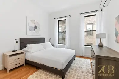 a bedroom with a bed and a desk and windows at Gorgeous and Fully Equipped Luxury 1 Bedroom Apt in New York