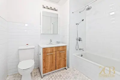 a white bathroom with a toilet and a sink and a tub at Gorgeous and Fully Equipped Luxury 1 Bedroom Apt in New York