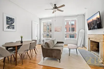 a living room with a table and chairs and a fireplace at Sun-Filled Brownstone Apt in Prime Chelsea in New York