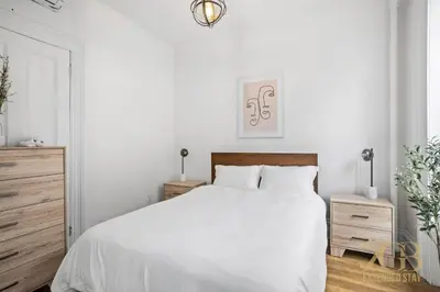a white bedroom with a white bed and wooden furniture at Sun-Filled Brownstone Apt in Prime Chelsea in New York