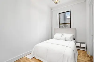 a white bedroom with a white bed and a window at Sun-Filled Brownstone Apt in Prime Chelsea in New York