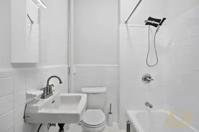 a white bathroom with a toilet and a sink at Sun-Filled Brownstone Apt in Prime Chelsea in New York