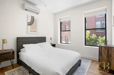 a white bedroom with a bed and two windows at Renovated 2 Bed 2 Bath Apt in Prime Midtown - Elevator - Laundry in New York