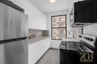 a kitchen with white cabinets and a sink and a window at State-of-the-Art Loft-Style 2Br Apartment - Laundry - Chelsea in New York