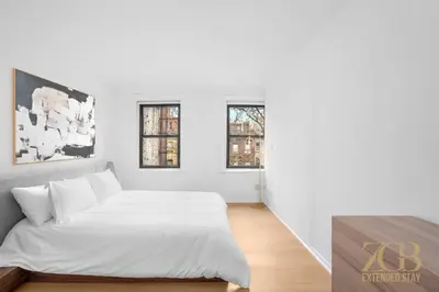a white bedroom with a bed and two windows at State-of-the-Art Loft-Style 2Br Apartment - Laundry - Chelsea in New York