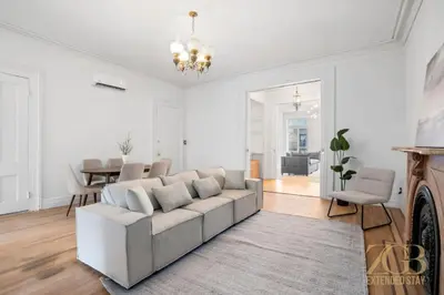 a white living room with a couch and a dining room at Classic NYC Brownstone 2Br Apartment in Prime Chelsea in New York