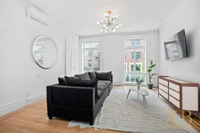 a living room with a black couch and a mirror at Classic NYC Brownstone 2Br Apartment in Prime Chelsea in New York
