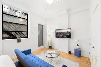 a living room with a blue couch and a glass table at Beautifully Renovated Studio in Prime Manhattan in New York