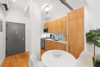 a white kitchen with a white table and white chairs at Beautifully Renovated Studio in Prime Manhattan in New York