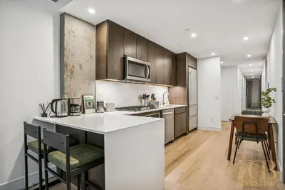 a kitchen with a white counter and wooden cabinets at Modern 2BR with WD in Elevator Building in NoMad in New York