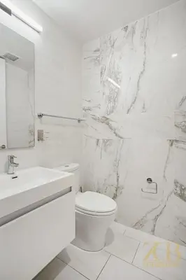 a white bathroom with a toilet and a sink at Modern 2BR with WD in Elevator Building in NoMad in New York