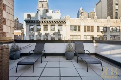 two chairs on a balcony with a view of a city at Modern 2BR with WD in Elevator Building in NoMad in New York