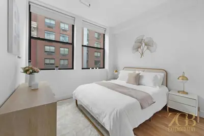 a white bedroom with a large bed and two windows at Beautifully Renovated 1 bedroom in Prime Manhattan in New York