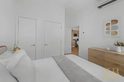 a white bedroom with a bed and a dresser at Beautifully Renovated 1 bedroom in Prime Manhattan in New York