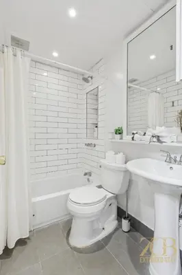 a white bathroom with a toilet and a sink at Spacious 3BR Flex 4 with Washer & Dryer in NoMad in New York