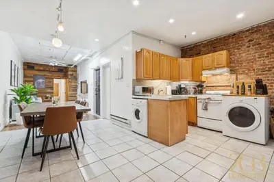 a kitchen with white appliances and a brick wall at Spacious 3BR Flex 4 with Washer & Dryer in NoMad in New York