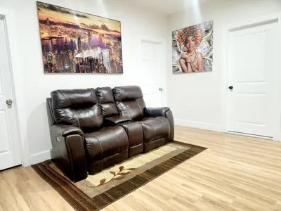 a brown leather couch in a room with two paintings at Cozy 2BR in Newark for Families, Work & Long Stays in Newark