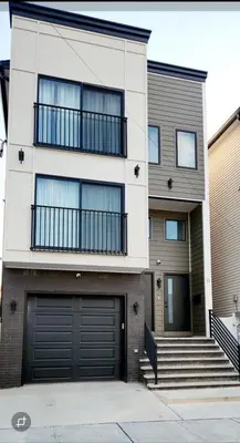 a white house with a garage and stairs at Cozy 2BR in Newark for Families, Work & Long Stays in Newark
