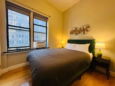 a bedroom with a large bed and two windows at Cortland Manhattan Suites in New York