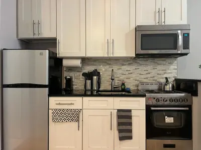 a kitchen with white cabinets and a white refrigerator at Cortland Manhattan Suites in New York