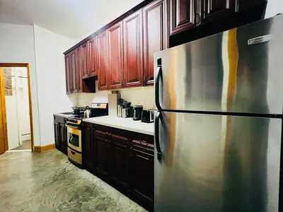 a kitchen with a stainless steel refrigerator and wooden cabinets at The Kensington on 44th in New York