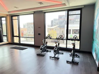 a gym with cardio bikes in a room with large windows at Luxury Stay Near NYC | Full Access to Amenities in Newark