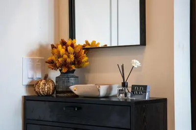 a dresser with a mirror and a vase with flowers on it at Luxury Stay Near NYC | Full Access to Amenities in Newark