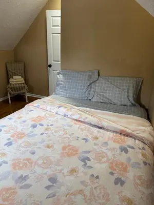 a bed with a floral comforter and a pillow at Cozy room with Queen bed 20 min to NYC in Ridgefield Park