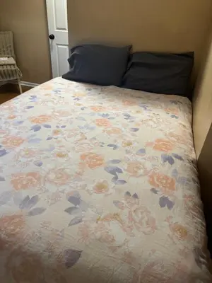 a bed with a floral comforter on it at Cozy room with Queen bed 20 min to NYC in Ridgefield Park