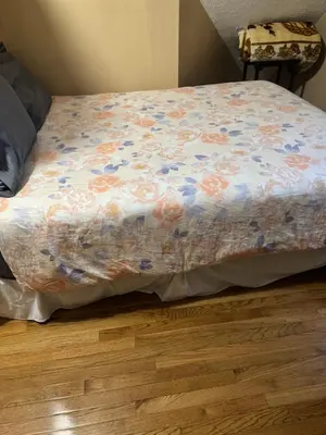 a bed with a floral blanket on top of a wooden floor at Cozy room with Queen bed 20 min to NYC in Ridgefield Park