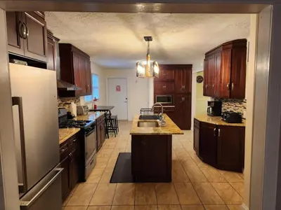 a kitchen with wooden cabinets and a sink and a refrigerator at Cozy 4 Bedrooms Pool Game Room in Tobyhanna