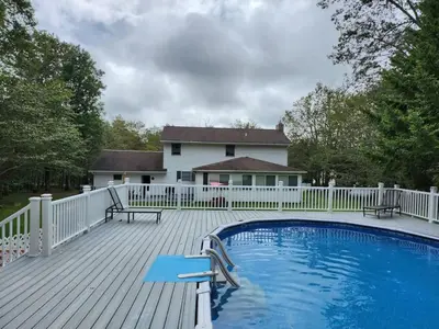 a deck with a pool and a white fence at Cozy 4 Bedrooms Pool Game Room in Tobyhanna