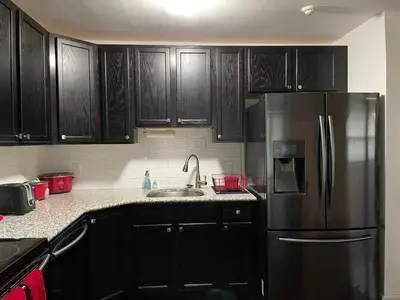 a kitchen with black cabinets and a stainless steel refrigerator at Fantastic updated apartment with parking in Glenside