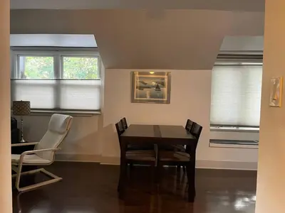 a dining room with a table and chairs and two windows at Fantastic updated apartment with parking in Glenside