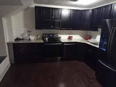 a kitchen with black cabinets and a black refrigerator at Fantastic updated apartment with parking in Glenside