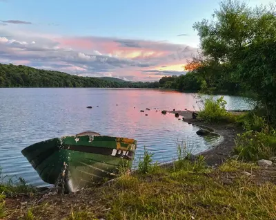 a green boat sitting on the shore of a lake at Modern Lakeview Escape | Scenic Deck • Fire Pit in Monroe